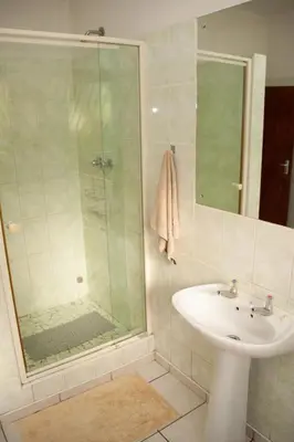a bathroom with a glass shower and a sink at Cairos Guest House in Witbank
