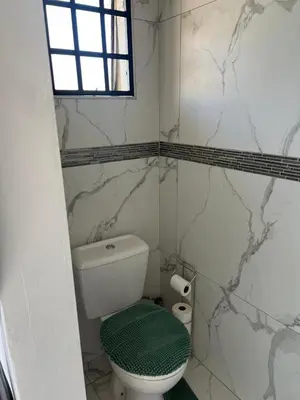 a white bathroom with a toilet and a window at 22 impala Ave in Kempton Park