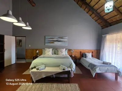 a bedroom with two beds and a window at Veldjie Huis in Temba