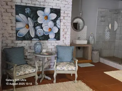 a bathroom with two chairs and a table and a painting at Veldjie Huis in Temba