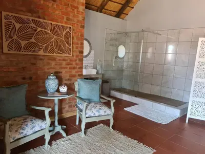 a bathroom with a tub and a table and chairs at Veldjie Huis in Temba