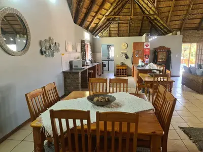 a dining room with a table and chairs and a kitchen at Veldjie Huis in Temba