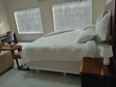 a bedroom with a large bed with white sheets and pillows at Wildlife Oasis in Marloth Park