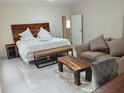 a bedroom with a bed and a couch and a table at Wildlife Oasis in Marloth Park