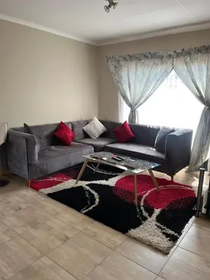 a living room with a gray couch with red pillows at Modern Style Apartments, An Escape From The City in Pretoria