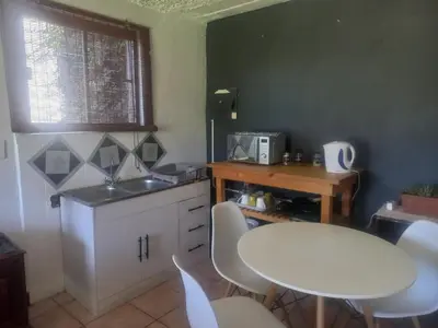 a kitchen with a white table and chairs and a sink at Ormonde guesthouse in Pretoria
