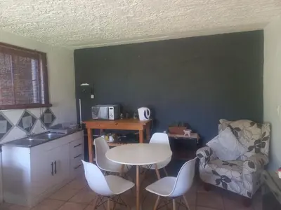 a kitchen with a table and chairs and a table and a chair at Ormonde guesthouse in Pretoria