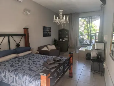 a bedroom with a large bed and a living room at Ormonde guesthouse in Pretoria