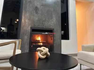 a fireplace in a living room with a table in front of it at Wabi Sabie River House in Hazyview