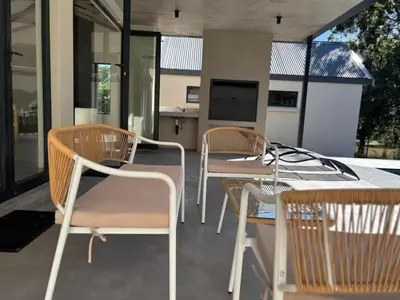 a patio with chairs and a table and a television at Wabi Sabie River House in Hazyview