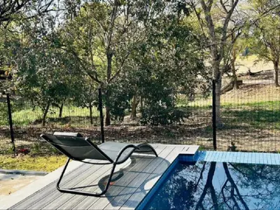 a chair sitting on a deck next to a swimming pool at Wabi Sabie River House in Hazyview