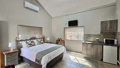 a bedroom with a bed and a kitchen with a microwave at The Magalies Nest - Self Catering Accomodation in Hartbeespoort