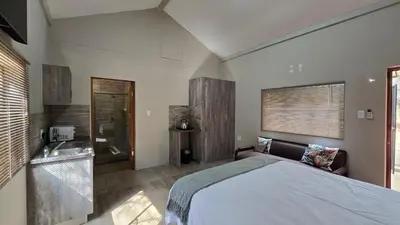 a bedroom with a large bed and a bathroom at The Magalies Nest - Self Catering Accomodation in Hartbeespoort