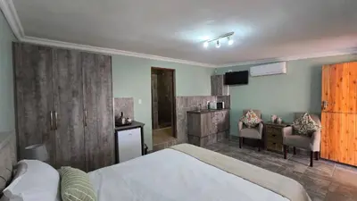 a bedroom with a bed and a desk and a television at The Magalies Nest - Self Catering Accomodation in Hartbeespoort
