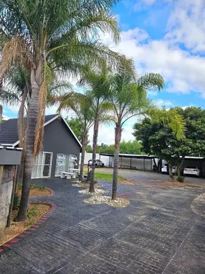 a group of palm trees in front of a house at Bella Cottage in Centurion