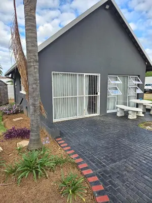 a gray house with a bench and a tree at Bella Cottage in Centurion