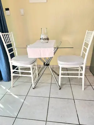 two chairs and a glass table with a vase on it at Bella Cottage in Centurion