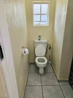 a bathroom with a toilet and a window at Bella Cottage in Centurion