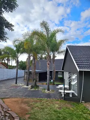 a house with palm trees in front of it at Bella Cottage in Centurion