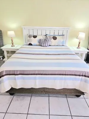 a bedroom with a large white bed with two lamps at Bella Cottage in Centurion