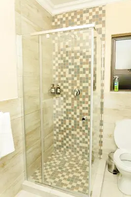 a shower with a glass door in a bathroom at Hamisi Manor Guest House in Midrand