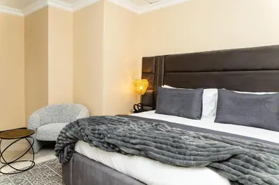 a bedroom with a large bed and a chair at Hamisi Manor Guest House in Midrand