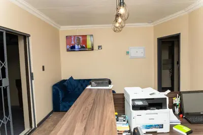 a living room with a blue couch and a printer at Hamisi Manor Guest House in Midrand