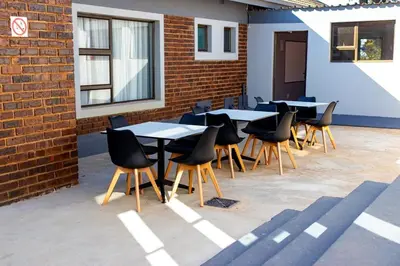 a row of tables and chairs next to a brick wall at Glowti Event & Guest House in Centurion