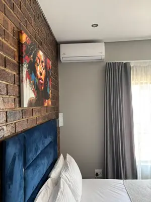 a bedroom with a brick wall and a bed at Glowti Event & Guest House in Centurion