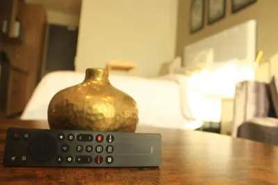 a remote control next to a vase on a table at 423 Menlyn maine Apartment in Pretoria