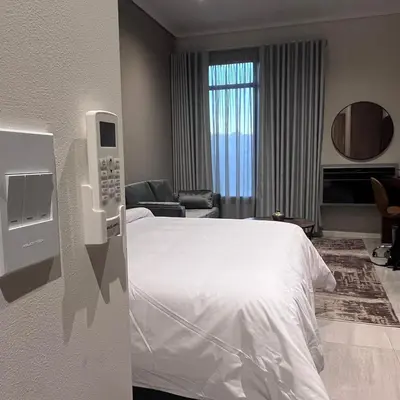 a hotel room with a white bed and a phone at 423 Menlyn maine Apartment in Pretoria
