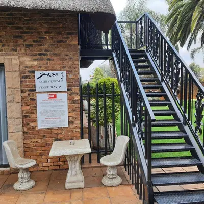 a stairway with two chairs and a table next to a building at Oppiplot Guest House Pty Ltd in Kempton Park