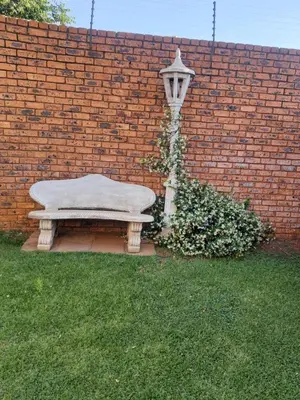 a stone bench next to a brick wall with a street light at Oppiplot Guest House Pty Ltd in Kempton Park
