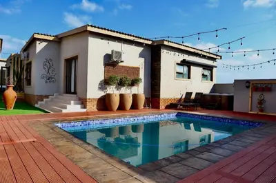 a house with a swimming pool in front of a house at Marble Nights Guesthouse and spa Elim in Elim