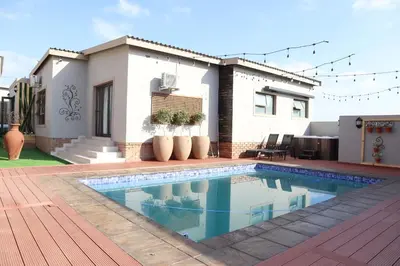 a swimming pool in front of a house at Marble Nights Guesthouse and spa Elim in Elim