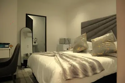 a bedroom with a large white bed with gold pillows at Marble Nights Guesthouse and spa Elim in Elim