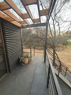 a covered porch of a house with a fence at Harties Damview Resort in Hartbeespoort