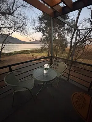 a table and chairs on a porch with a view of a lake at Harties Damview Resort in Hartbeespoort