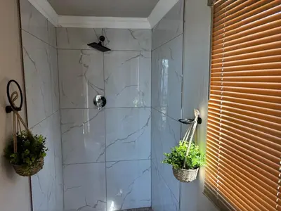 a bathroom with a glass shower with two potted plants at Harties Damview Resort in Hartbeespoort