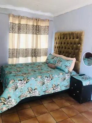 a bedroom with a bed with a blue comforter at Christland Guest House in Kempton Park