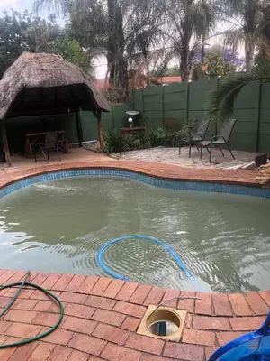 a swimming pool with a hose in the water at Christland Guest House in Kempton Park