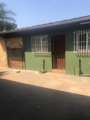 a green building with two doors on the side of it at Christland Guest House in Kempton Park