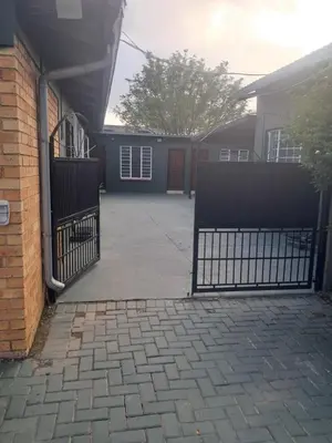 a driveway with a black gate and a house at Christland Guest House in Kempton Park