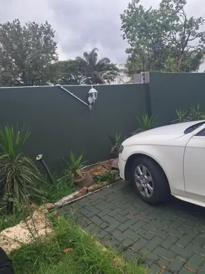 a white car parked in front of a fence at Christland Guest House in Kempton Park