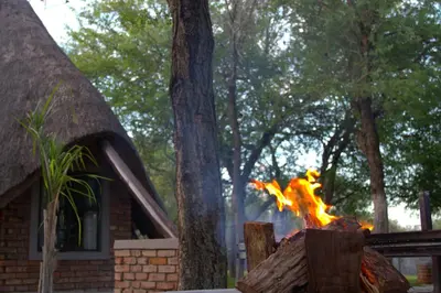 a fire is burning in front of a house at Selukwe Safari Lodge in Marloth Park