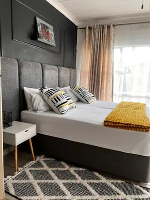 a bedroom with a bed with pillows and a window at Luxury Airport Flatlet in Kempton Park