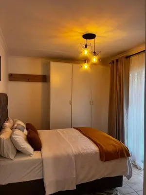 a bedroom with a large bed and a chandelier at Luxury Airport Flatlet in Kempton Park
