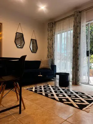 a living room with a black couch and a rug at Luxury Airport Flatlet in Kempton Park