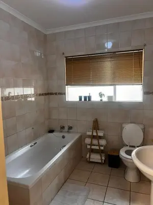 a bathroom with a tub and a toilet and a sink at Luxury Airport Flatlet in Kempton Park