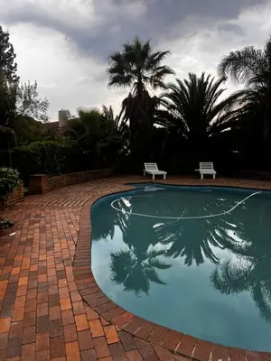 a swimming pool with a reflection of a palm tree at Luxury Airport Flatlet in Kempton Park